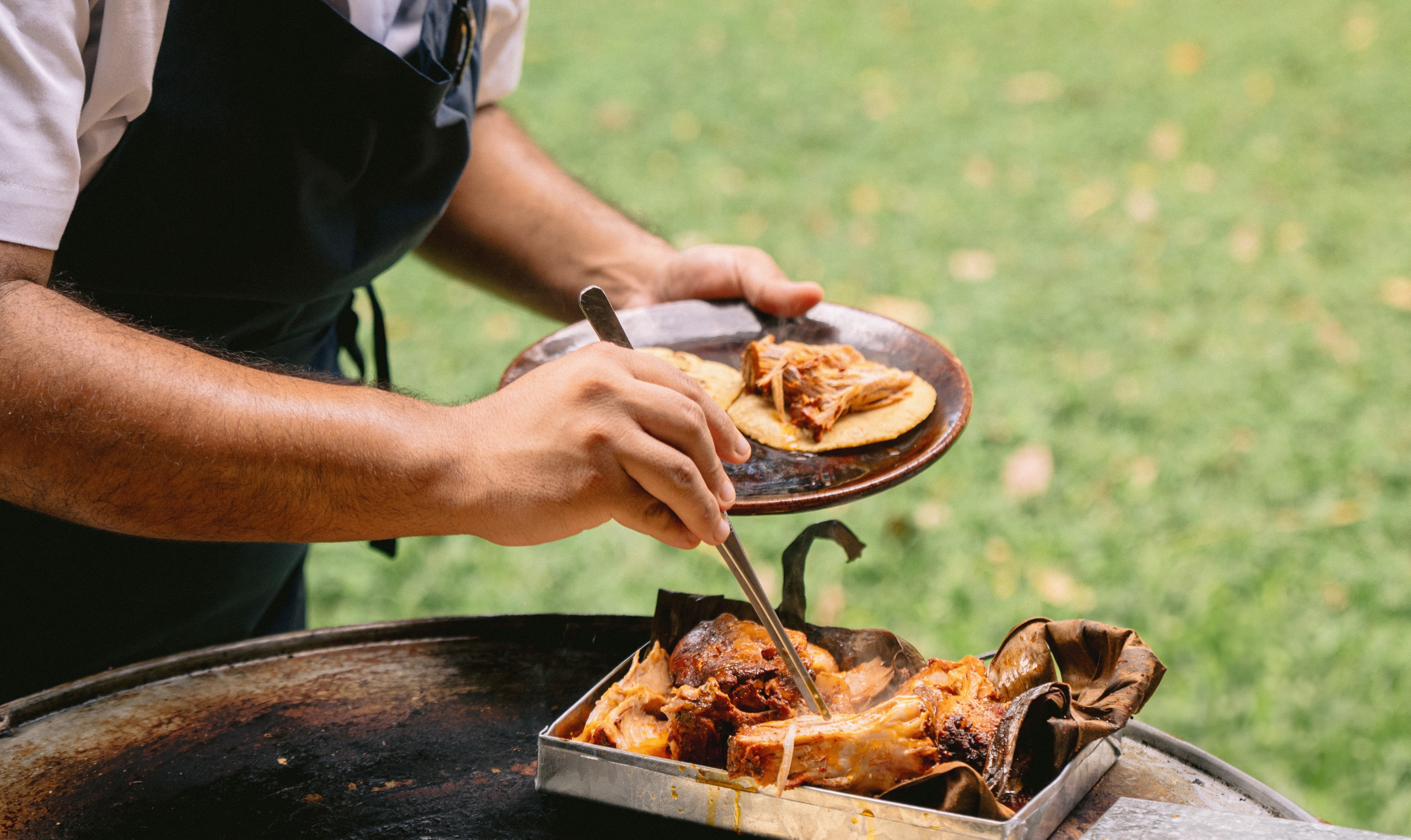 Chef serves tacos from a tray, showcasing vibrant cooking at Hacienda Xcanatun, Angsana Heritage Collection.